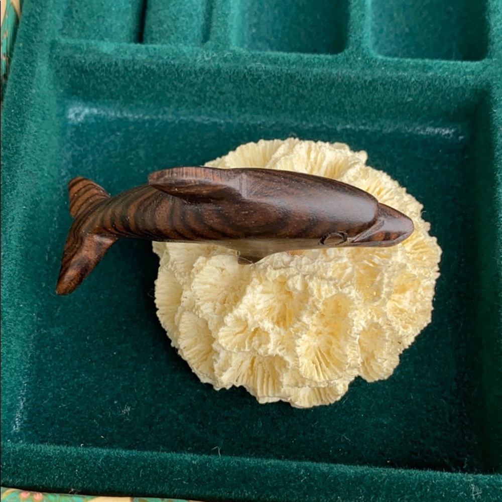 Small hand carved wooden dolphin on coral